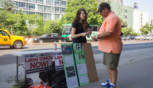 A woman from New York Public Interest Research Group speaks to a passerby about the potential dangers of GMOs in front of a Whole Foods Market in New York on June 3, 2014. (Jonathan Zhou/Epoch Times)