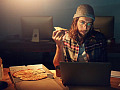 Maneating a pizza in front of a screen.